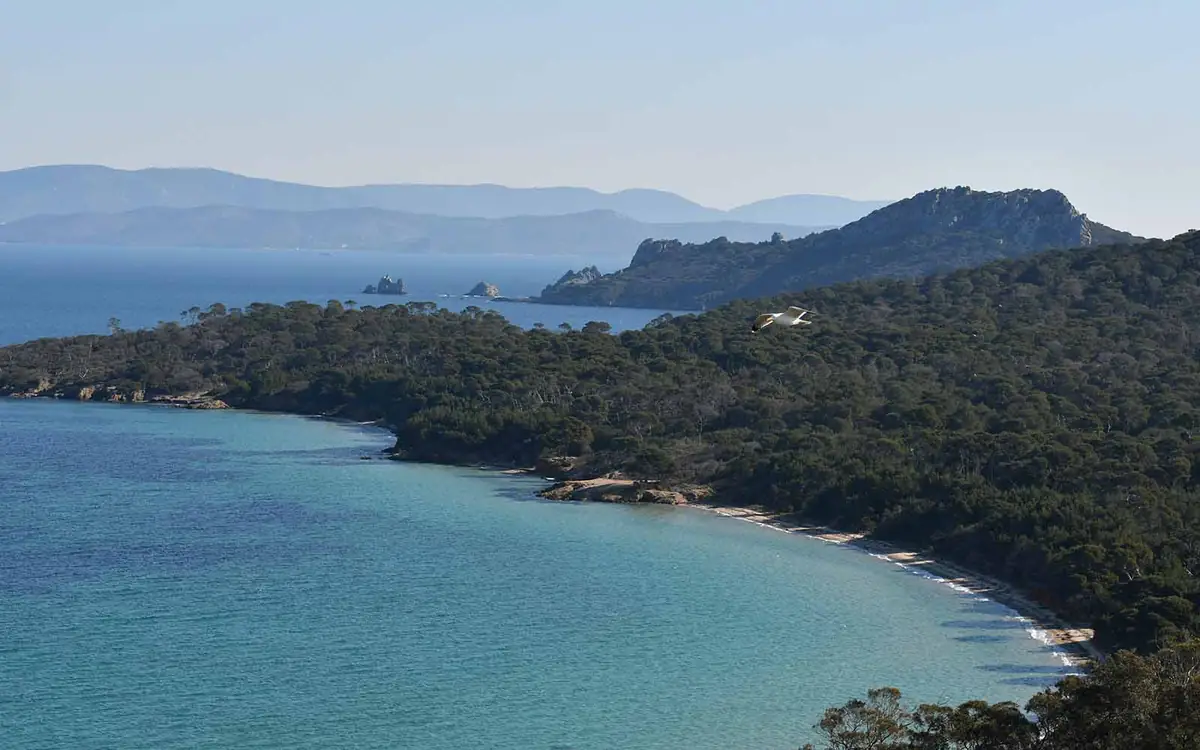Baie aux eaux turquoise entourée de collines boisées
