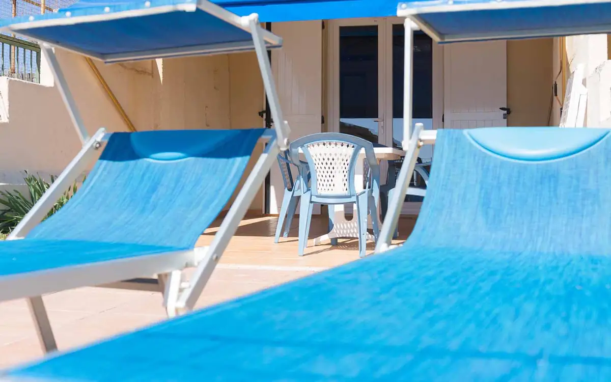 Transats bleus et salon de jardin sur une terrasse abritée